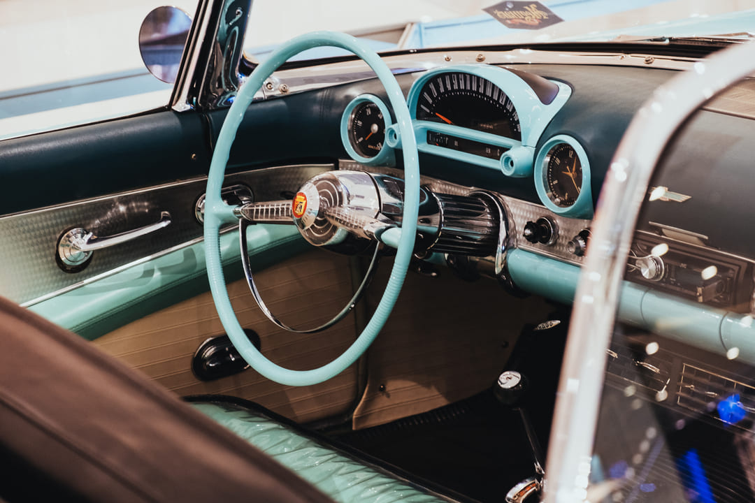 Painel de carro clássico com volante vintage azul e detalhes cromados, ideal para amantes de carros antigos e colecionadores.