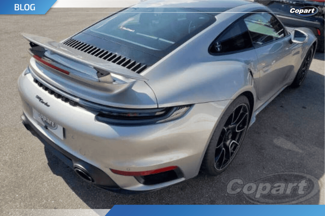 Traseira de um Porsche 911 Turbo S prata, com aerof&oacute;lio elevado e design esportivo &mdash; destaque do mercado de luxo automotivo e desejado entre compradores premium.