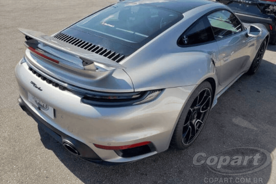 Traseira de um Porsche 911 Turbo S prata, com aerofólio elevado e design esportivo — destaque do mercado de luxo automotivo e desejado entre compradores premium.