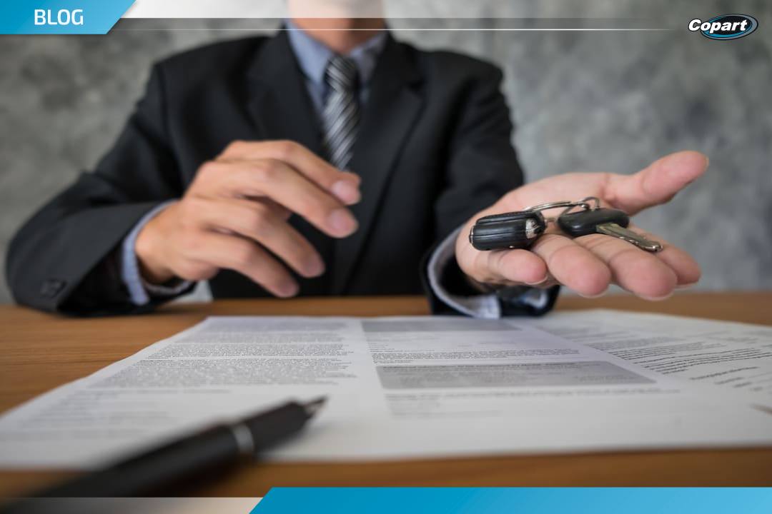 Homem entregando chave de carro sobre contrato assinado, simbolizando finaliza&ccedil;&atilde;o de compra em leil&atilde;o de ve&iacute;culos.