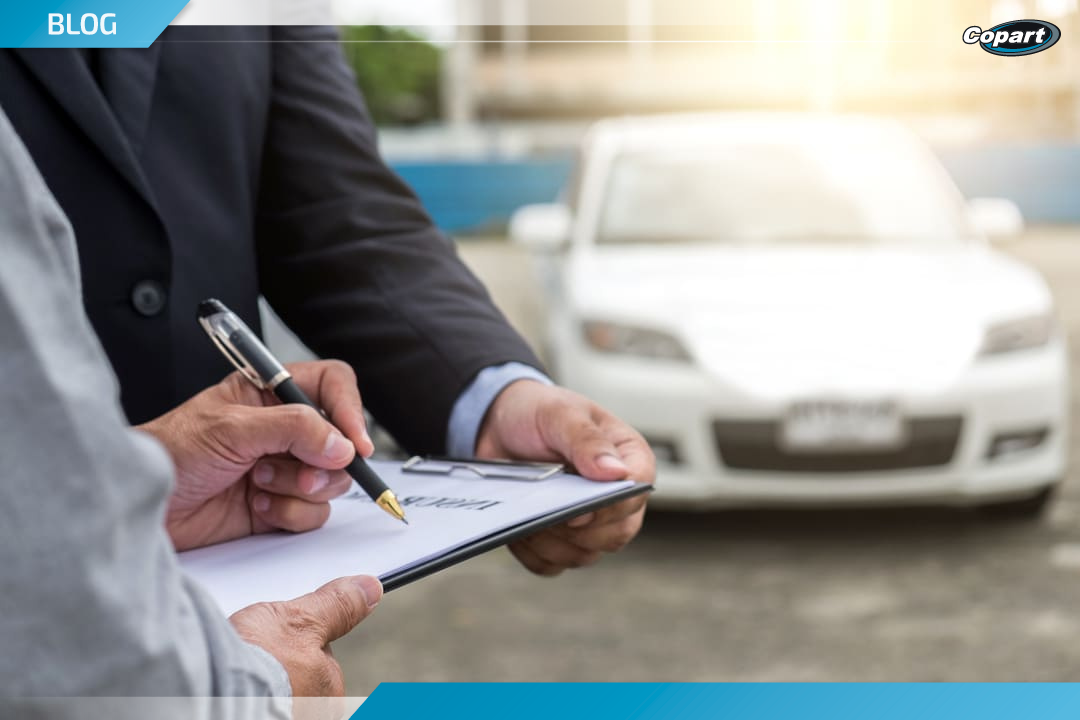 Pessoa assinando documentos com carro ao fundo, representando compra em leil&atilde;o de ve&iacute;culos.
