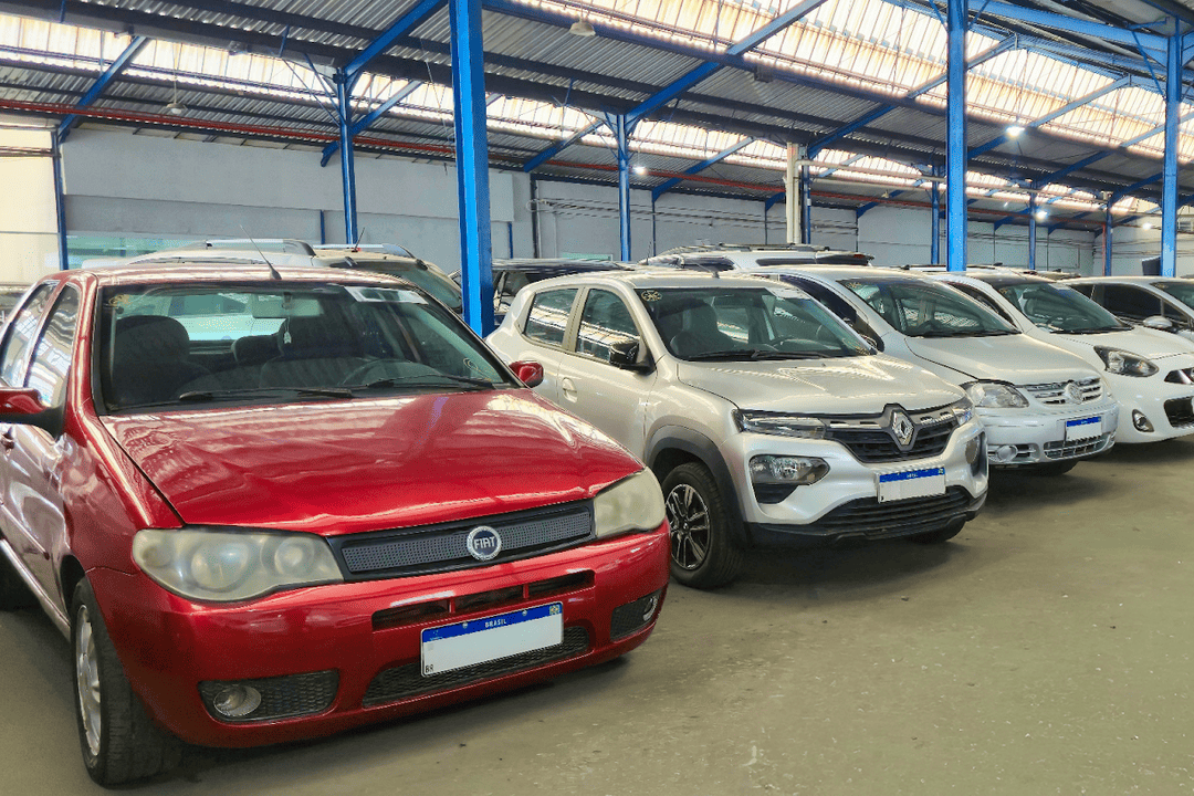 Carros usados expostos em concessionária de seminovos.