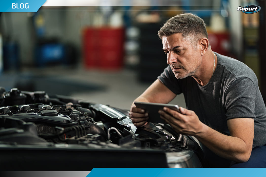 Mecânico analisando o motor de um carro com auxílio de um tablet, representando o uso de inteligência artificial no mercado automotivo.